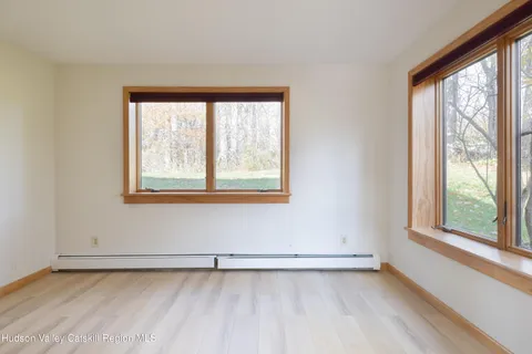 a view of an empty room with a window and wooden floor