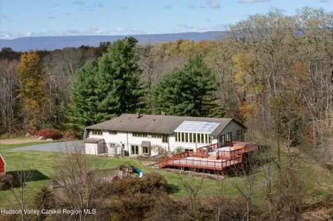 an aerial view of a house with garden space and trees all around