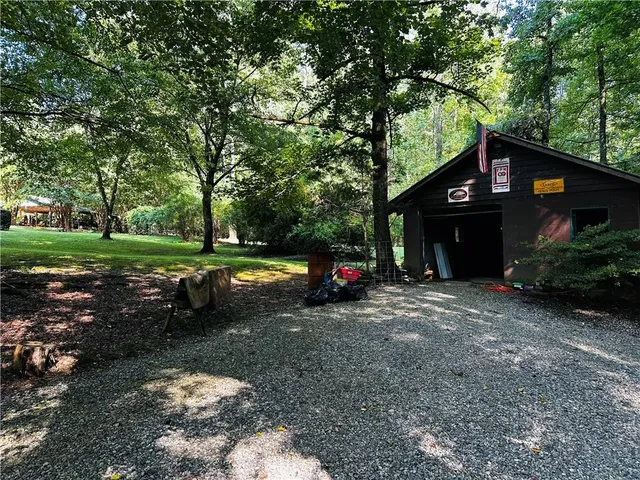 a view of a swimming pool with lawn chairs and large trees