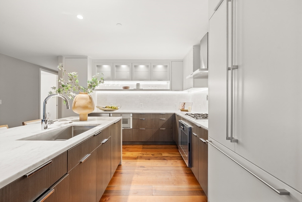 300 Pier 4 Blvd., Unit 7G Boston, MA 02210 - Photo 8 of 39 a large kitchen with a sink and dishwasher a stove top oven with wooden floor