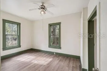 a view of an empty room with a window and wooden floor