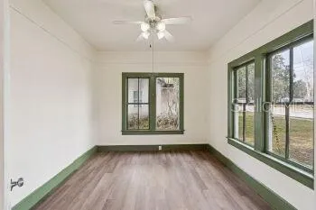 a view of an empty room with a window and wooden floor