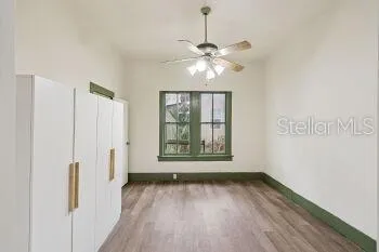 a view of an empty room with a window and wooden floor