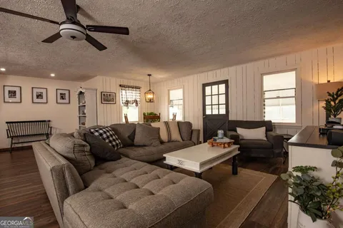 a living room with furniture kitchen view and a window