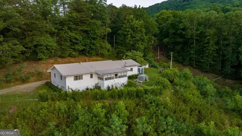 an aerial view of residential house with outdoor space and trees all around