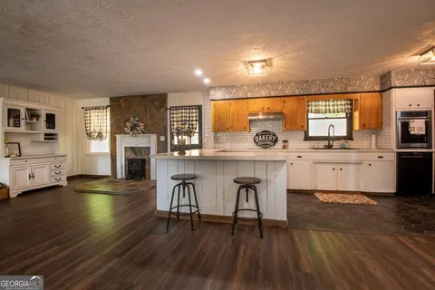 a kitchen with stainless steel appliances a kitchen island hardwood floor sink stove dining table and chairs