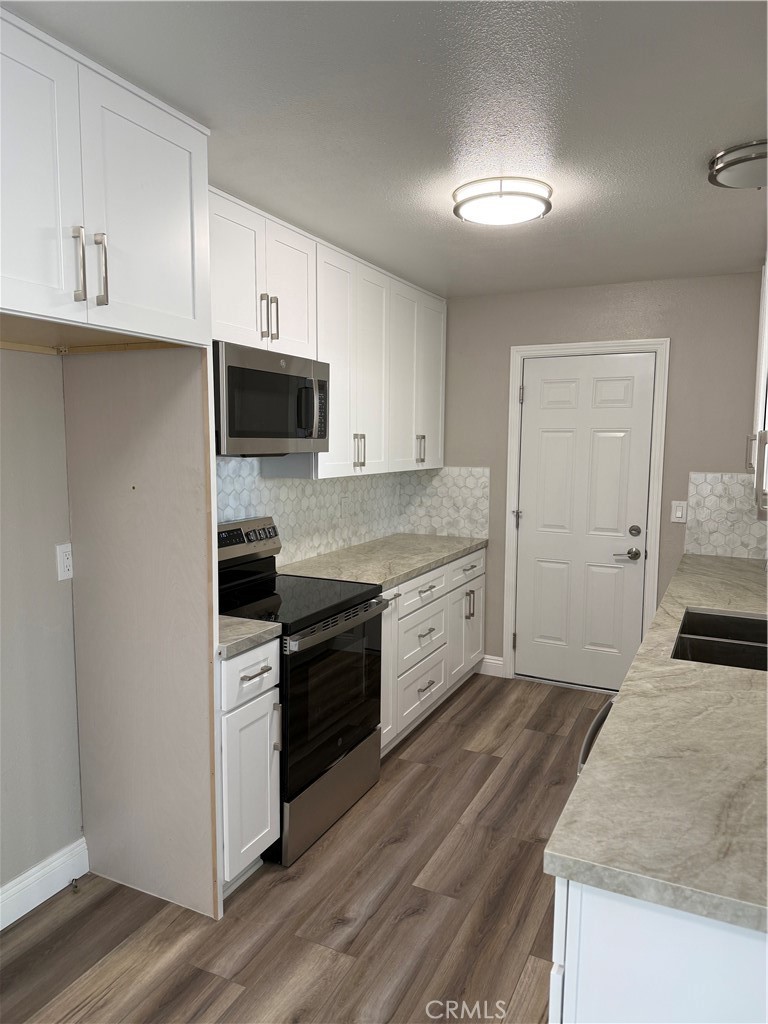 596 Opal Avenue Hemet, CA 92543 - Photo 8 of 30 a kitchen with granite countertop a stove top oven a sink dishwasher and a refrigerator with wooden cabinets