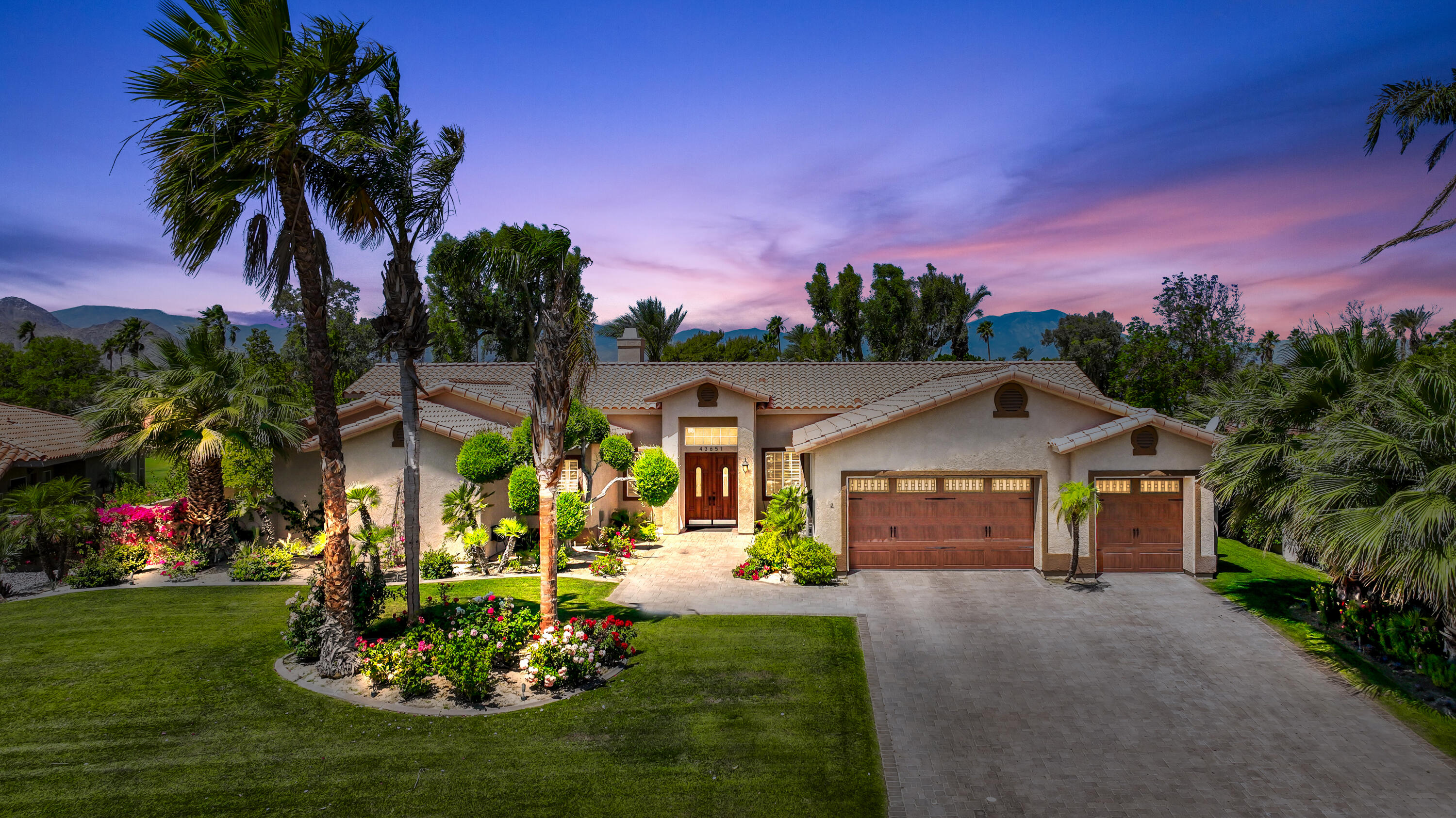 a front view of a house with a garden and tree