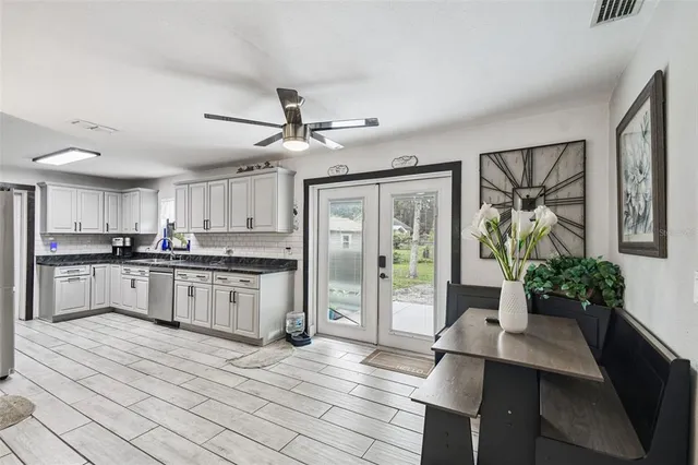 a kitchen with stainless steel appliances kitchen island granite countertop a refrigerator a stove a sink dishwasher and white cabinets with wooden floor