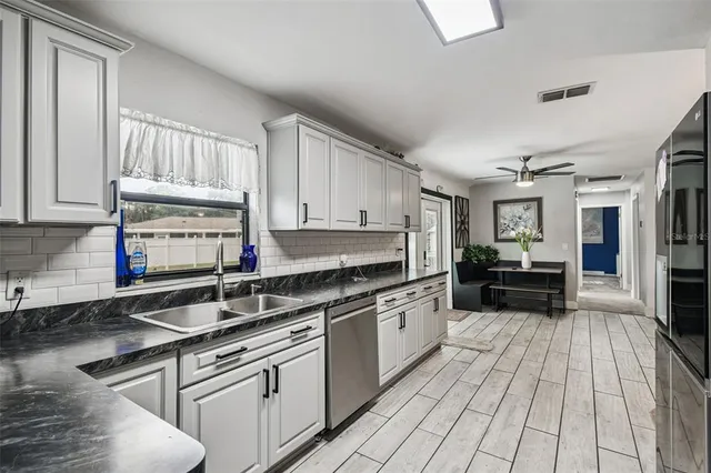 a kitchen with kitchen island granite countertop a sink cabinets and stainless steel appliances