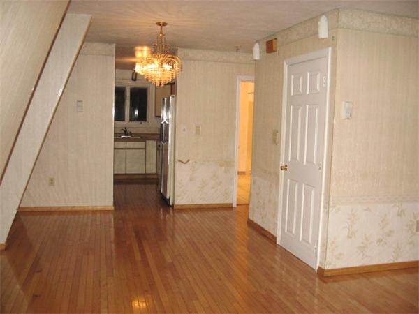 121 Copperfield Road Worcester, MA 01602 - Photo 5 of 18 a view of a hallway with wooden floor a kitchen space with a refrigerator and windows