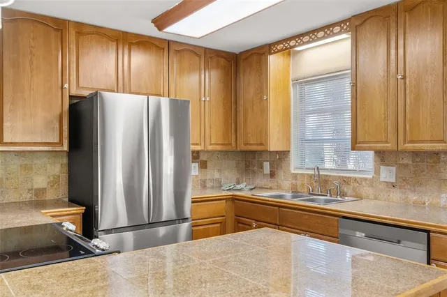a kitchen with stainless steel appliances granite countertop a refrigerator and a sink