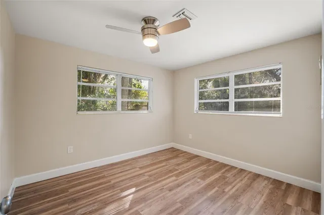 a view of empty room with wooden floor and fan