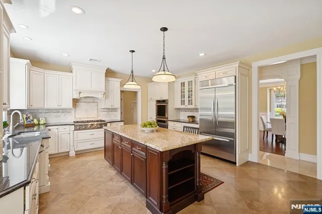 a large kitchen with kitchen island a large counter top space a sink appliances and cabinets