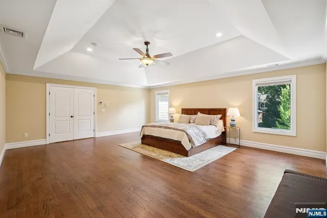 a spacious bedroom with a large bed a chandelier and windows