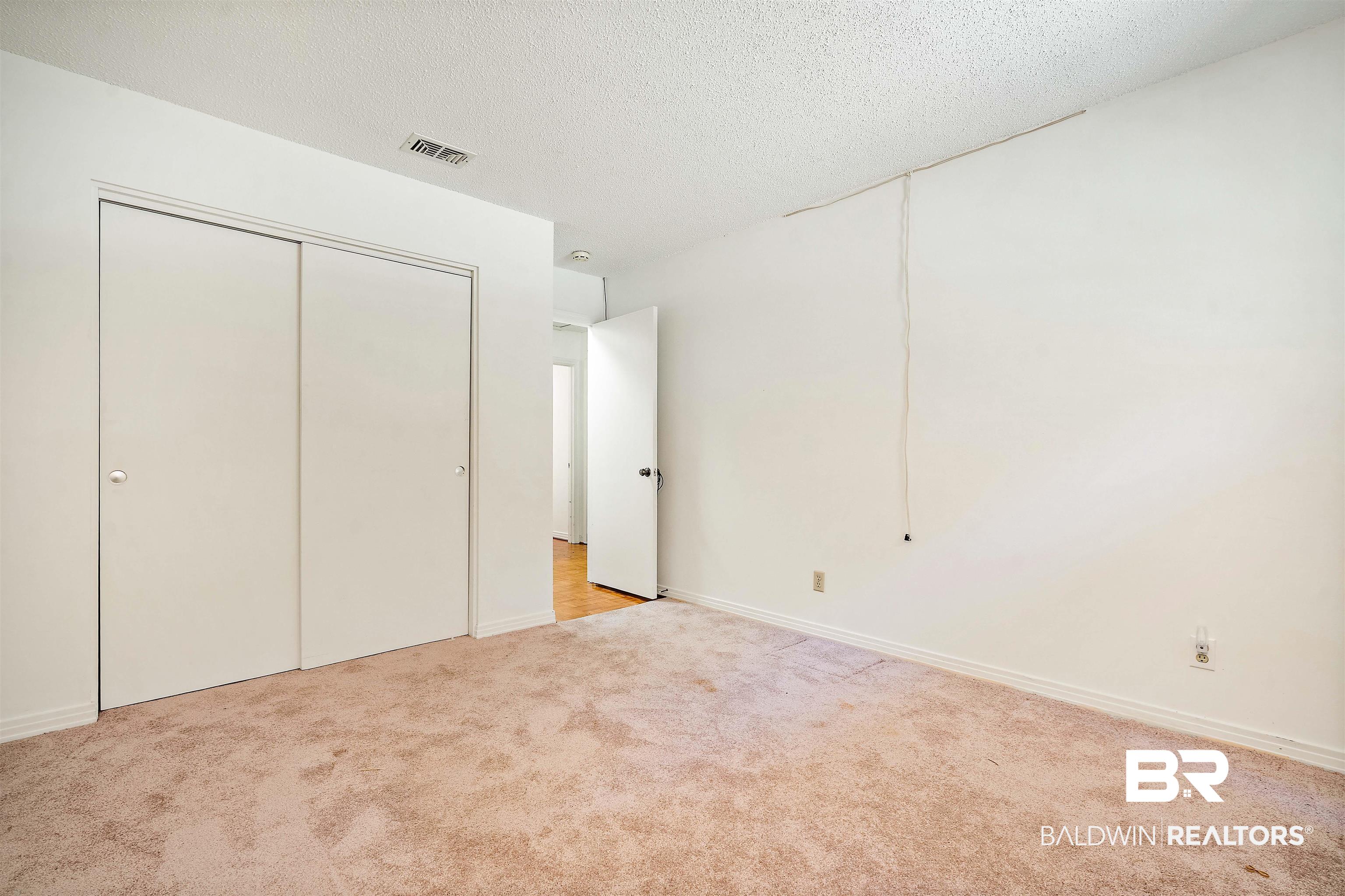 5559 Woodside Drive North Mobile, AL 36608 - Photo 6 of 28 Unfurnished bedroom with a textured ceiling, light carpet, and a closet