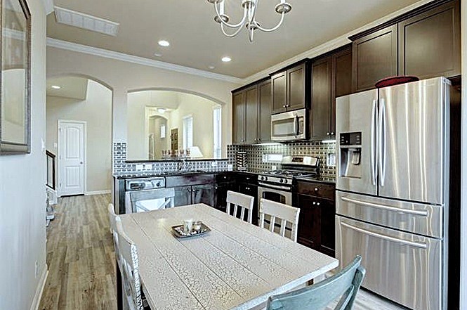 14001 Avery Ranch Boulevard, Unit 801 Austin, TX 78717 - Photo 15 of 26 A compact kitchen with sleek stainless steel appliances, dark wood cabinetry, and a mosaic tile backsplash.