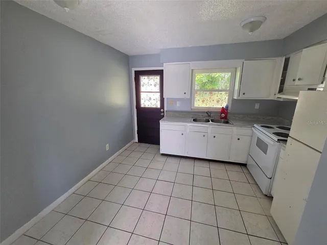 a kitchen with a sink a window and white cabinets