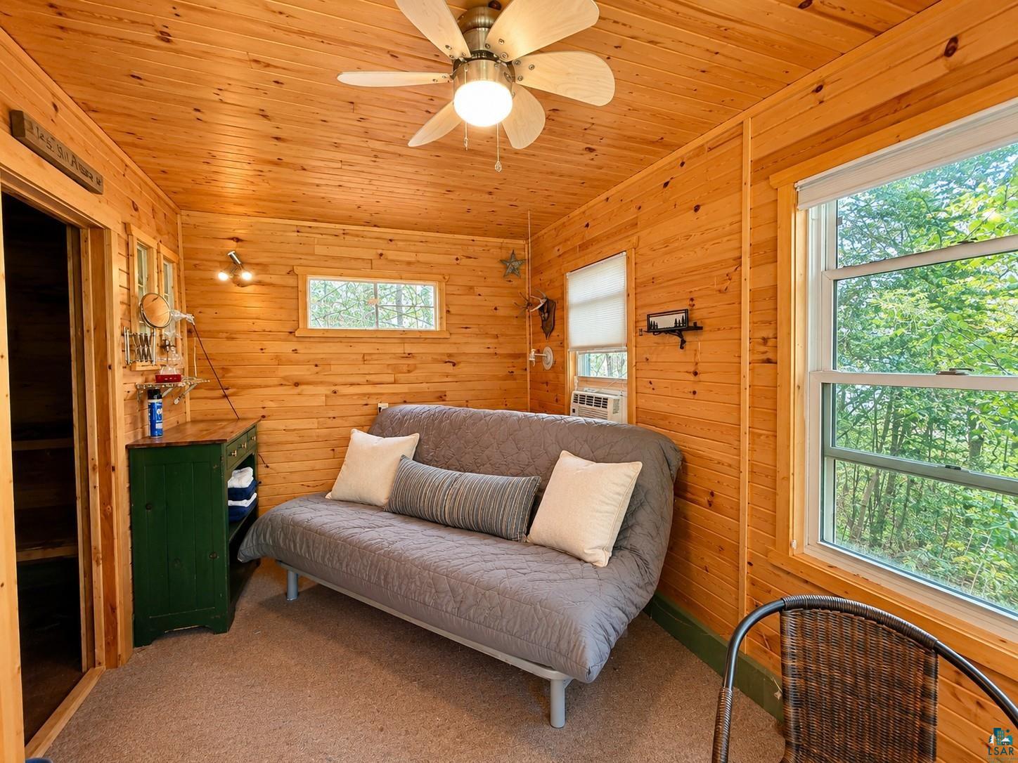 1787 North Bay Road Ely, MN 55731 - Photo 35 of 40 Wood-paneled room featuring a ceiling fan, wall-mounted light fixtures, and multiple windows