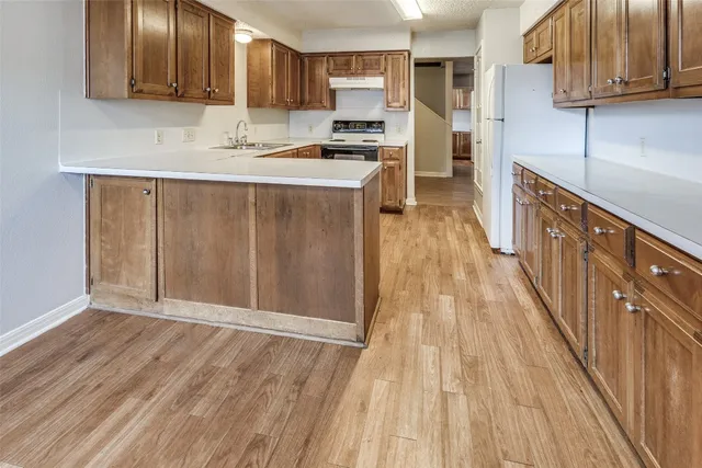 a kitchen with granite countertop wooden floors a sink and cabinets
