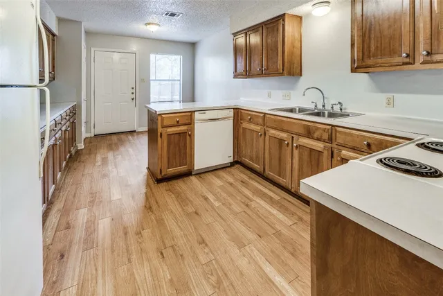 a kitchen with a sink a stove cabinets and wooden floor