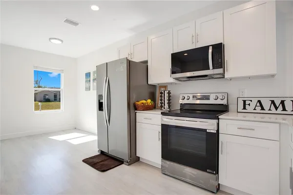 a kitchen with stainless steel appliances a stove a microwave and white cabinets