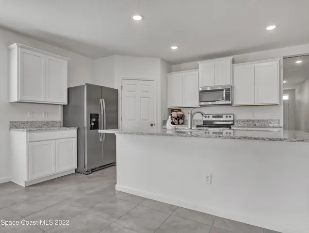 a kitchen with kitchen island a white cabinets and refrigerator