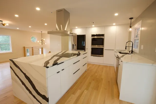 a large white kitchen with a large counter top and stainless steel appliances