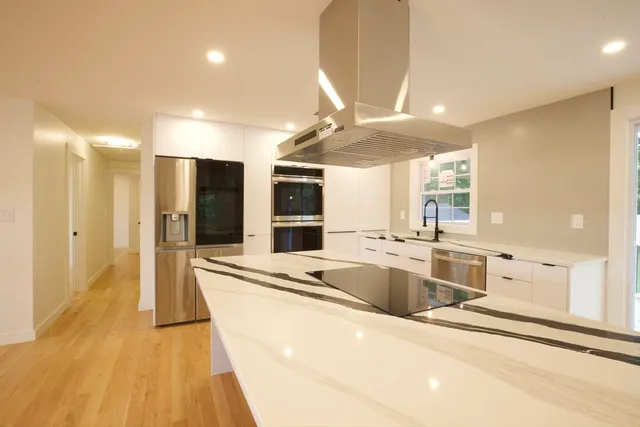 a large kitchen with kitchen island a large counter top space a sink stainless steel appliances and cabinets