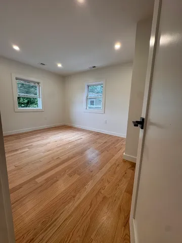 an empty room with wooden floor and window
