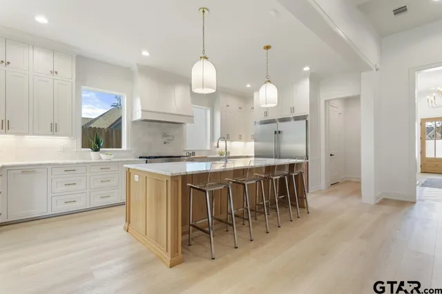 a kitchen with stainless steel appliances kitchen island granite countertop a stove a sink a oven a dining table and chairs with wooden floor