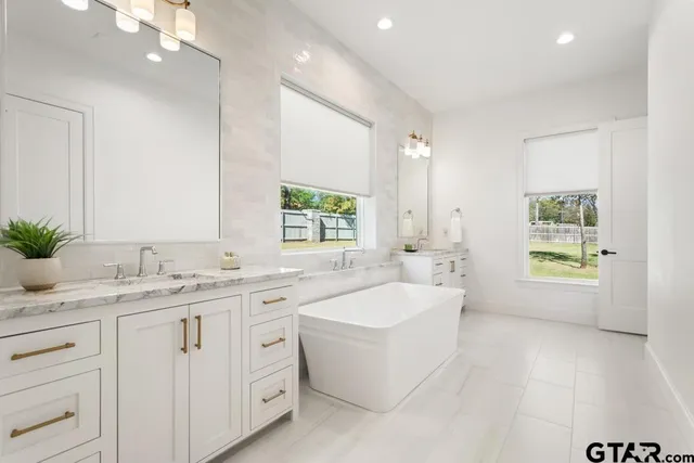 a bathroom with a granite countertop sink mirror and a bathtub