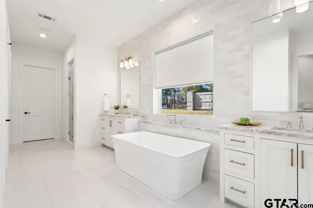 a spacious bathroom with a tub sink and mirror