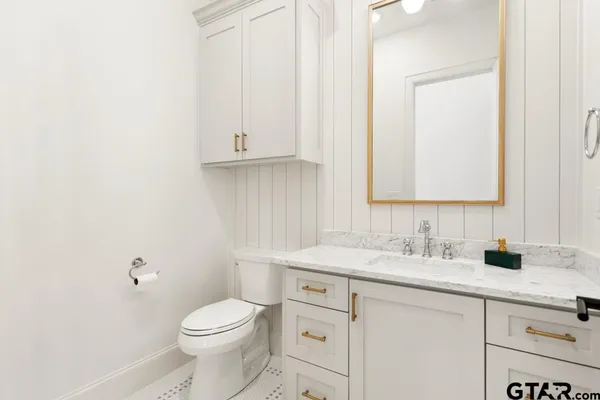 a bathroom with a granite countertop toilet sink and mirror