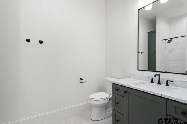 a bathroom with a granite countertop toilet a sink and a mirror
