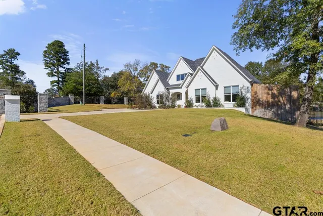 a view of a white house with a yard and palm trees