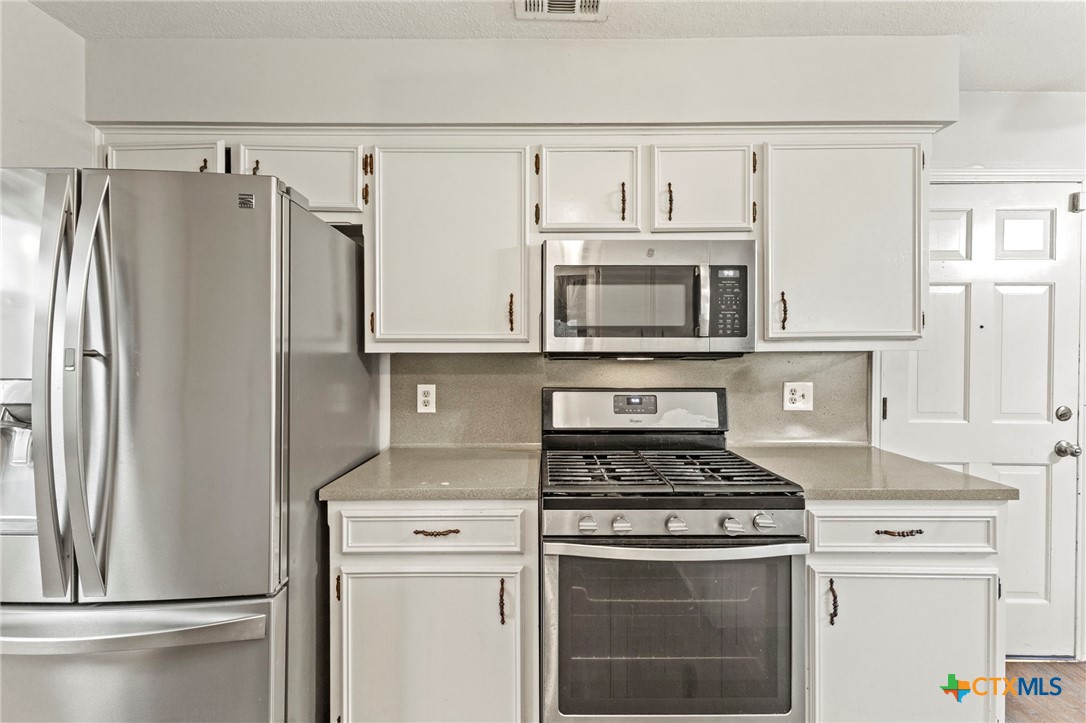 413 Suzzane Road Pflugerville, TX 78660 - Photo 11 of 23 Kitchen with appliances with stainless steel finishes, white cabinetry, and light stone countertops