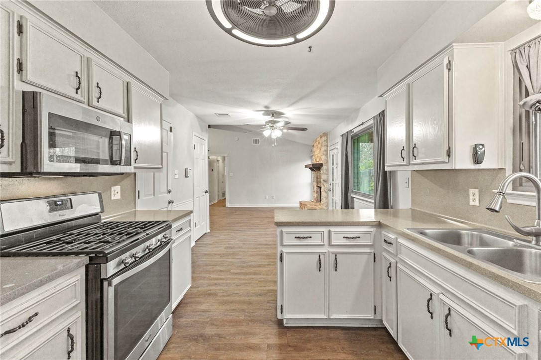 413 Suzzane Road Pflugerville, TX 78660 - Photo 12 of 23 Kitchen with stainless steel appliances, white cabinetry, a breakfast bar and light countertops is open to the dining area