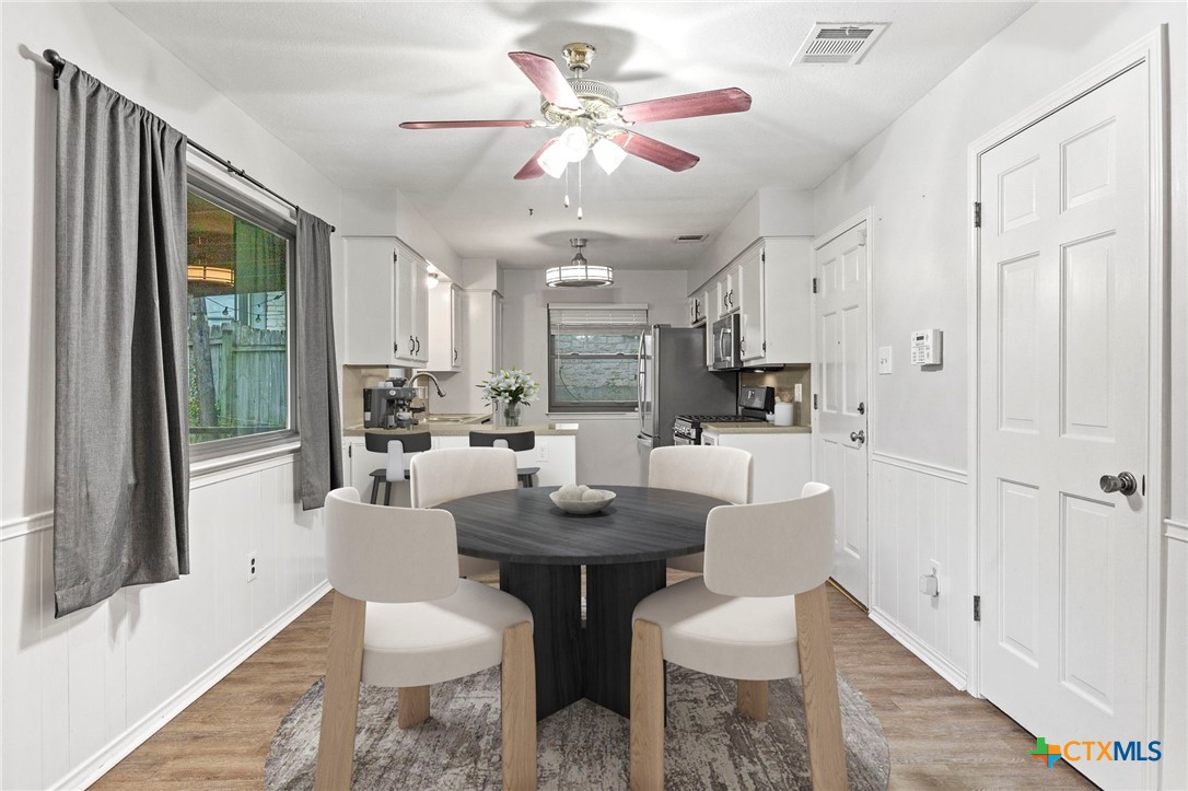 413 Suzzane Road Pflugerville, TX 78660 - Photo 3 of 23 Dining space is open to the kitchen with healthy amount of natural light, wood-style floors, ceiling fan, and a wainscoted wall. (virtually staged)