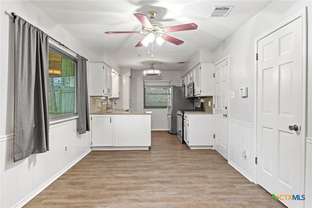 413 Suzzane Road Pflugerville, TX 78660 - Photo 8 of 23 Dining space is open to the kitchen with healthy amount of natural light, wood-style floors, ceiling fan, and a wainscoted wall.