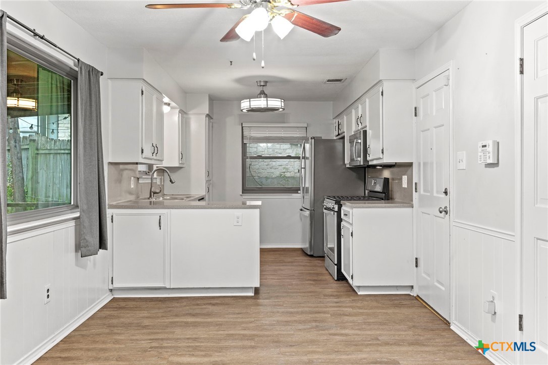 413 Suzzane Road Pflugerville, TX 78660 - Photo 9 of 23 Dining space is open to the kitchen with healthy amount of natural light, wood-style floors, ceiling fan, and a wainscoted wall.