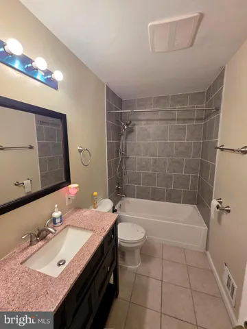 a bathroom with a granite countertop sink a toilet a mirror and bathtub