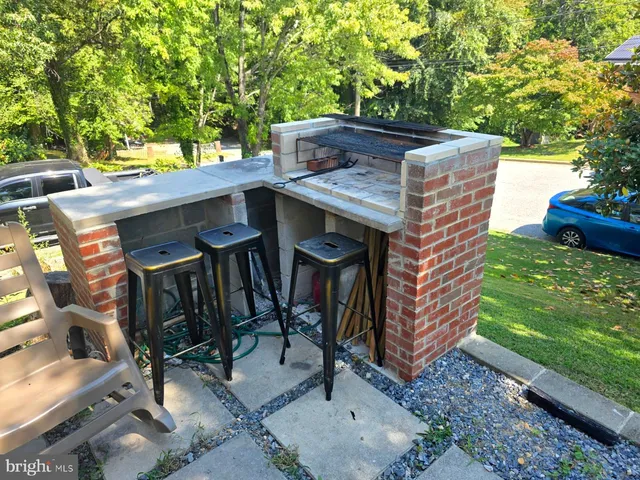 a view of a patio with table and chairs with a barbeque grill and a small yard
