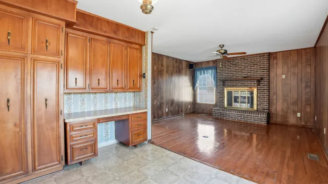 an empty room with wooden floor cabinet and windows