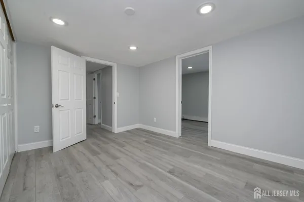 a view of an empty room with wooden floor and closet