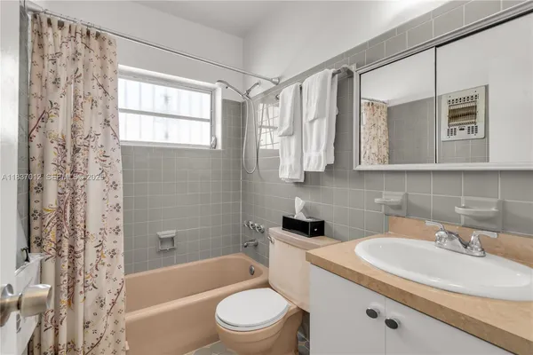 a bathroom with a sink a toilet a mirror a bathtub and shower