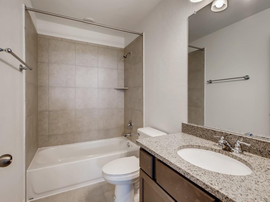 334 Pecos River Crossing Dripping Springs, TX 78620 - Photo 19 of 28 a bathroom with a granite countertop bathtub shower sink vanity mirror and toilet