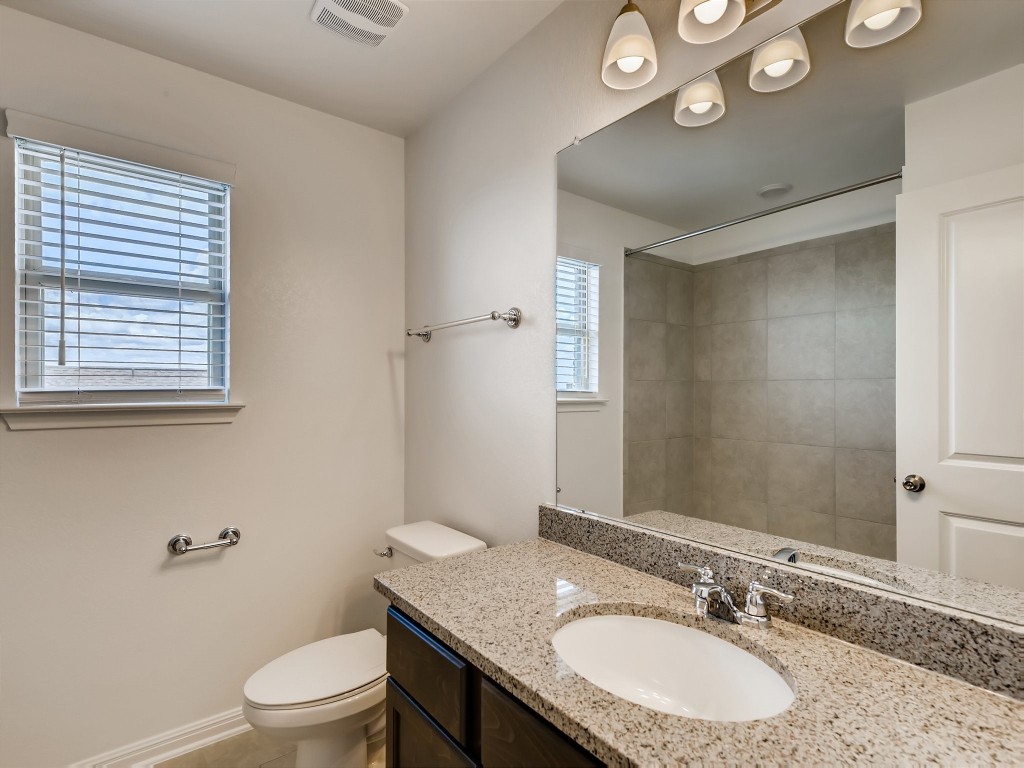 334 Pecos River Crossing Dripping Springs, TX 78620 - Photo 22 of 28 a bathroom with a granite countertop sink a toilet and a mirror