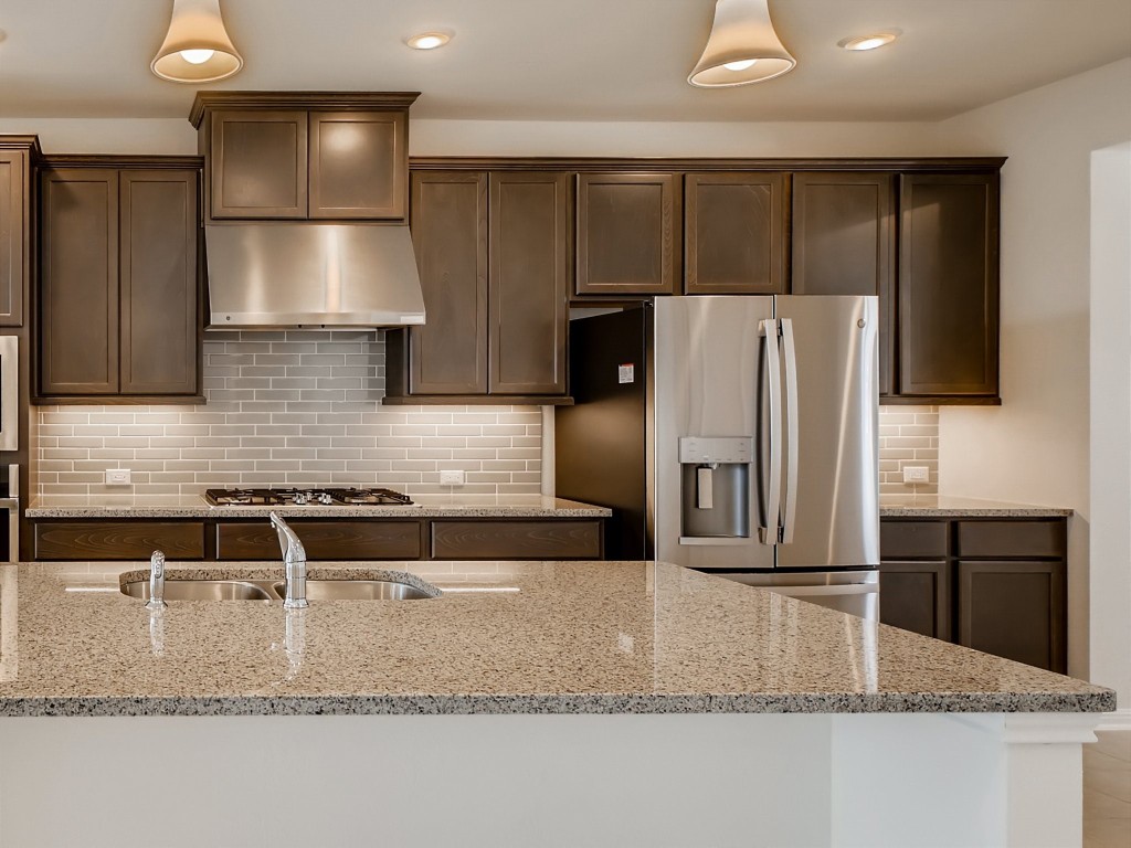 334 Pecos River Crossing Dripping Springs, TX 78620 - Photo 8 of 28 a kitchen with granite countertop a refrigerator a stove and kitchen island