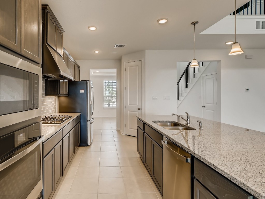 334 Pecos River Crossing Dripping Springs, TX 78620 - Photo 9 of 28 a kitchen with stainless steel appliances granite countertop a sink a stove and a refrigerator